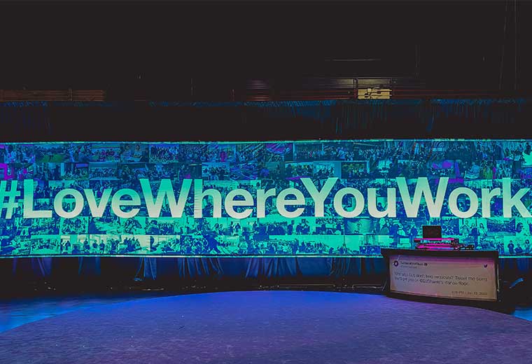 "love where you work" written on draping with lighting on a stage at an event